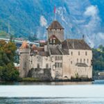 a castle sitting on top of a lake surrounded by mountains